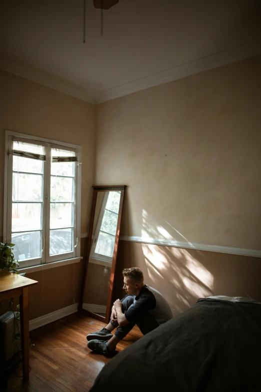 a person sitting on the floor in a room, australian tonalism, sun puddle, small bedroom, soft light - n 9, boy's room