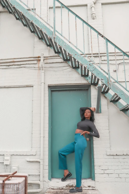 a woman sitting on the steps of a building, an album cover, by Dulah Marie Evans, pexels contest winner, teal uniform, wearing pants and a t-shirt, at a fashion shoot, tall door