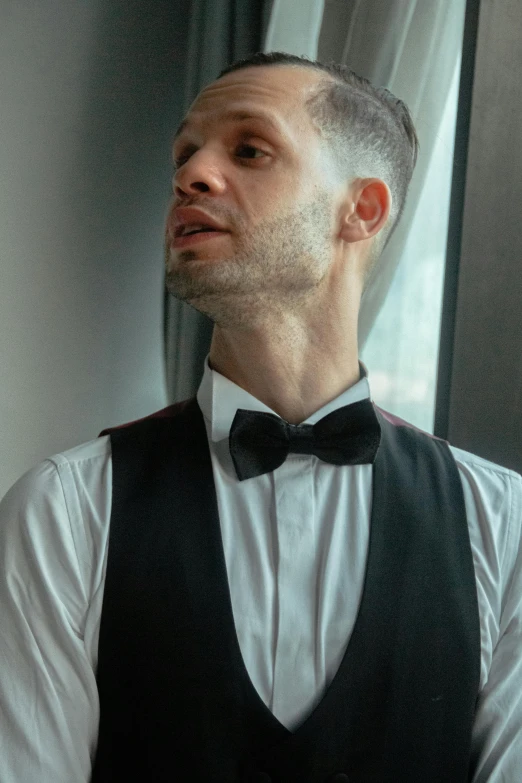 a man wearing a black vest and bow tie, inspired by Ramon Pichot, reddit, looking out, shaven, mid shot photo, matt howarth