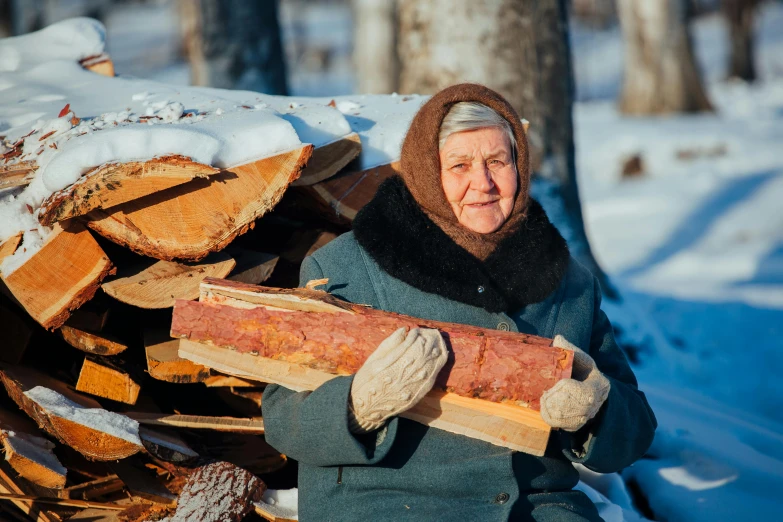 a woman holding a pile of wood in the snow, by Aleksandr Gerasimov, pexels contest winner, socialist realism, an old lady with red skin, woodfired, 🦩🪐🐞👩🏻🦳, avatar image