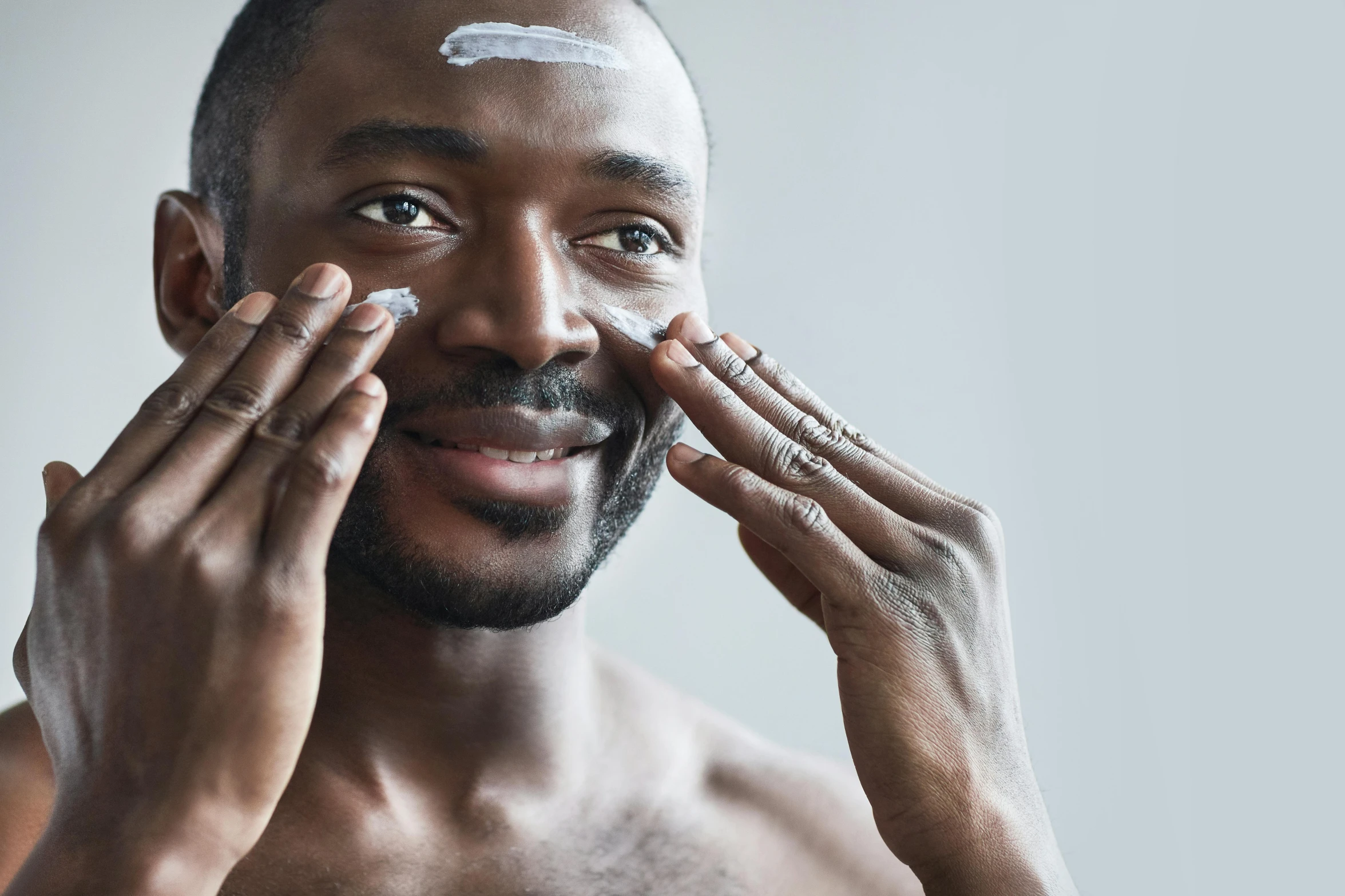 a man putting cream on his face, by Carey Morris, trending on pexels, square facial structure, african man, gilleard james, grey skin