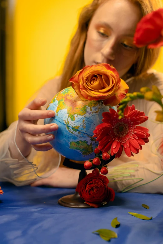 a woman holding a globe with flowers in it, an album cover, trending on pexels, close - up studio photo, video still, sustainability, sadie sink