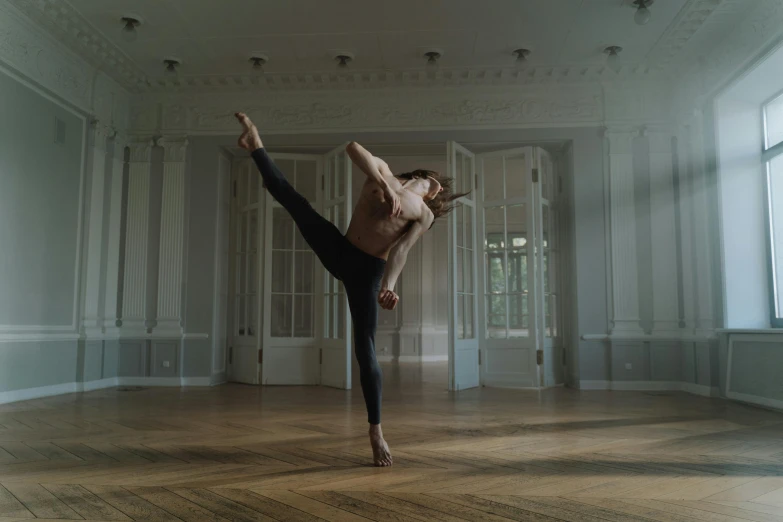 a woman doing a yoga pose in an empty room, by Emma Andijewska, arabesque, he is dancing, anton fadeev 8 k, leg and hip shot, felix englund