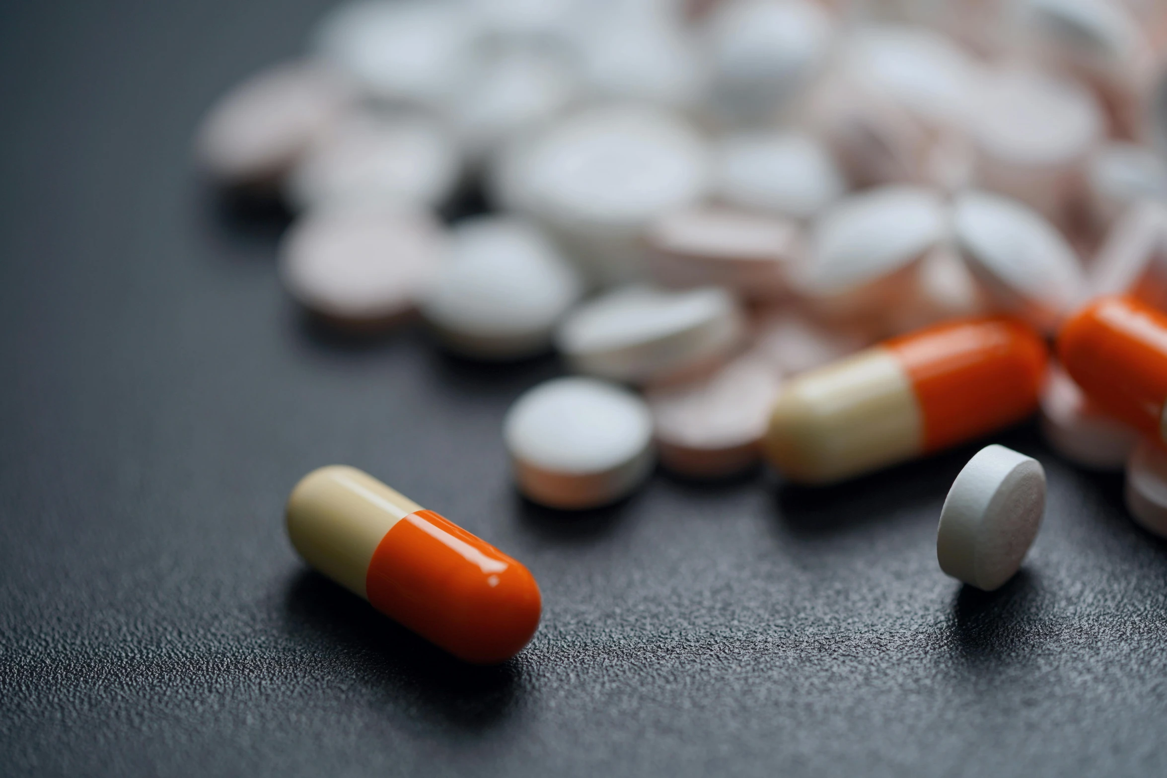 a pile of pills sitting on top of a table, unsplash, antipodeans, dark grey and orange colours, then another, paul barson, medical reference