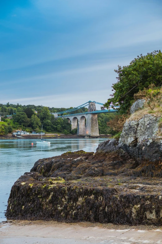 a large body of water with a bridge in the background, a photo, by Robert Fawcett, pembrokeshire, 4 k -, bay, tall