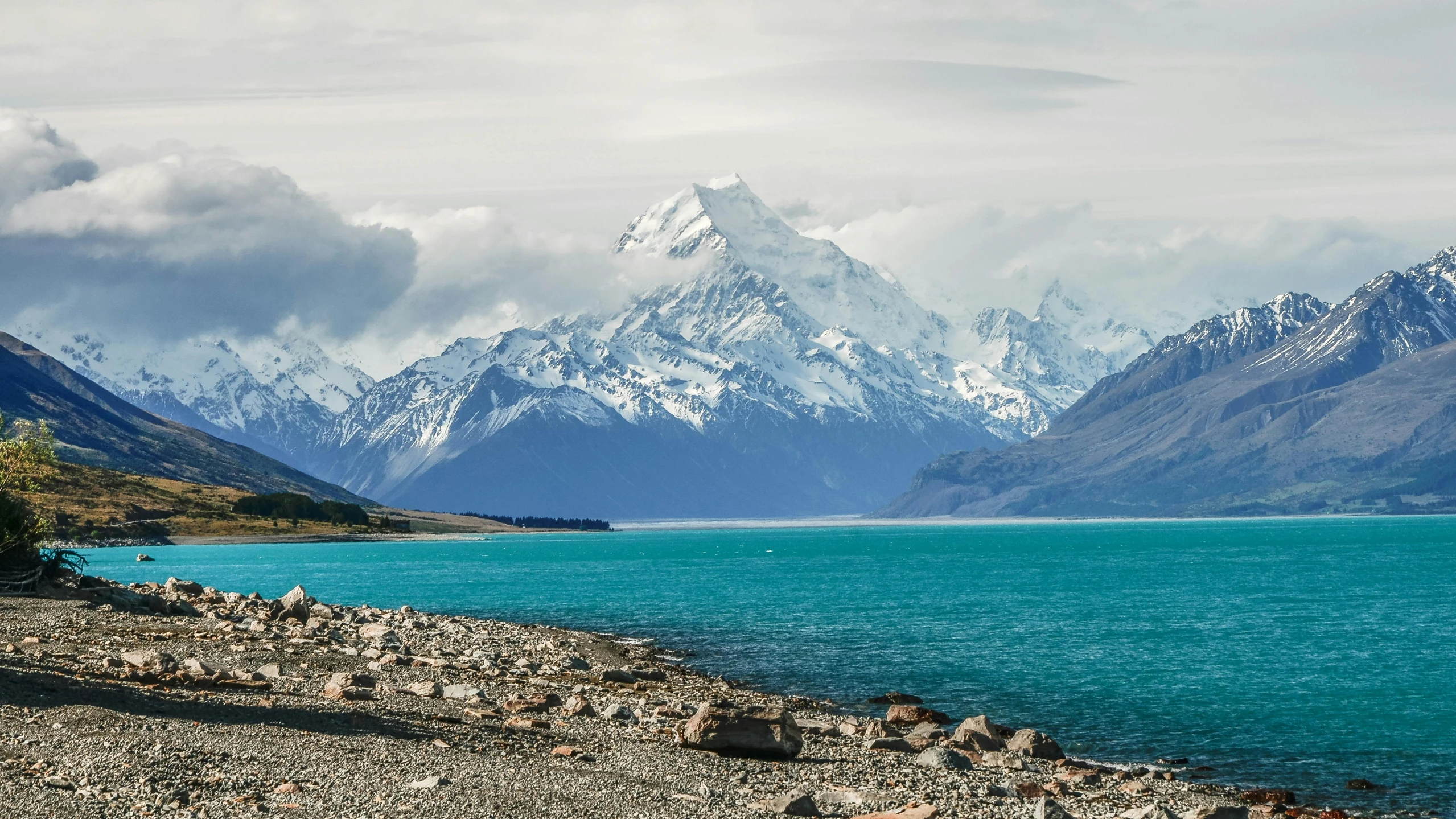 a large body of water with mountains in the background, by Charlotte Harding, unsplash contest winner, te pae, snowy mountain background, turquoise, ash thorp khyzyl saleem