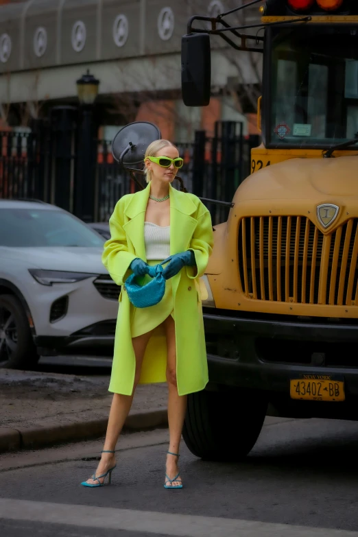 a woman standing in front of a school bus, by Sebastian Vrancx, at new york fashion week, lime green, 2019 trending photo, blond