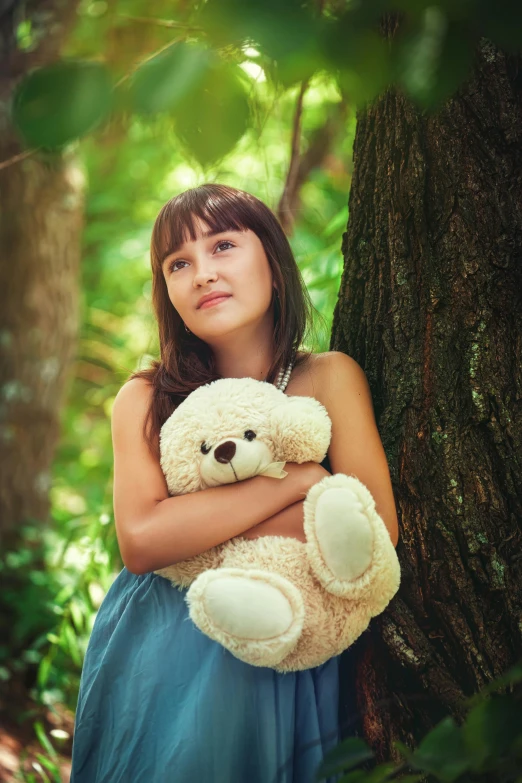 a girl in a blue dress holding a teddy bear, by Lilia Alvarado, pexels, on a tree, soft shade, thoughtful ), tan