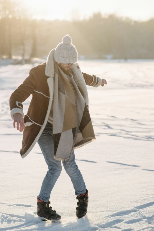 a man walking across a snow covered field, trending on pexels, she is dancing, light brown coat, sick with a cold, white