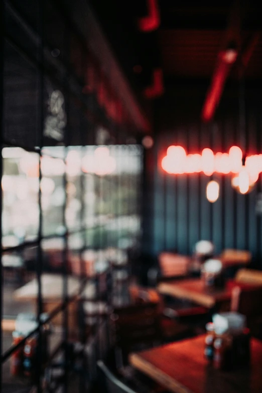 a blurry photo of a restaurant with tables and chairs, pexels contest winner, light and space, red neon, moody morning light, an illustration of a bar/lounge, light reflecting off windows