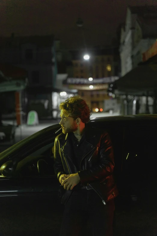 a man sitting in the passenger seat of a car, an album cover, by Jacob Toorenvliet, on a street at night, wearing a leather jacket, standing on street corner, movie still frame