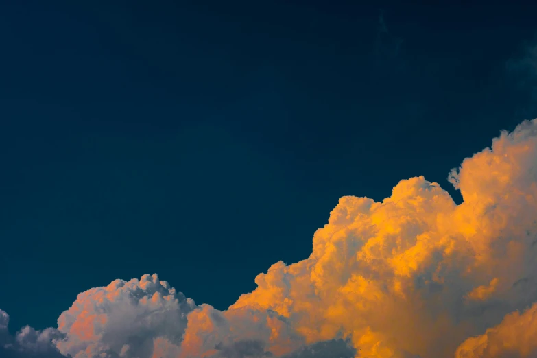 a plane flying through a cloudy blue sky, by Jan Rustem, unsplash, late summer evening, towering cumulonimbus clouds, orange and blue, color ektachrome photograph