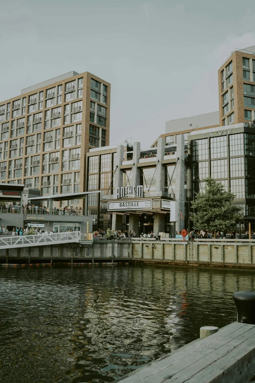 a couple of buildings next to a body of water, a picture, inspired by Washington Allston, unsplash, hurufiyya, docked at harbor, people walking around, mall, front facing shot