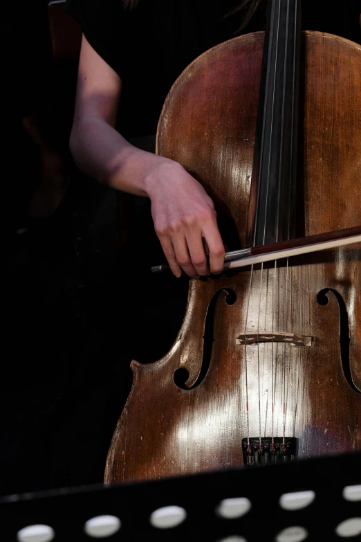 a close up of a person playing a cello, standing on top of a violin