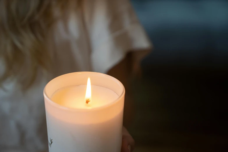 a person holding a lit candle in their hand, by Alice Mason, unsplash, private press, close up shot from the side, relaxing, soft white glow, handcrafted