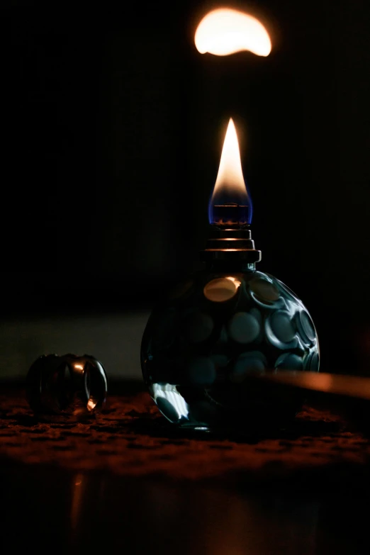 a lit candle sitting on top of a table, inspired by Joseph Wright of Derby, blue fireball, lava lamp, perfume bottle, raku