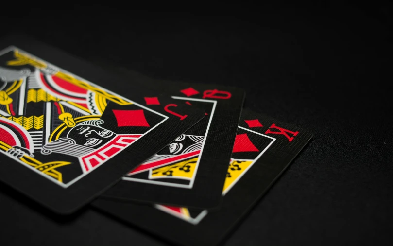 a couple of playing cards sitting on top of a table, black and yellow and red scheme, taken with sony alpha 9, artwork, black