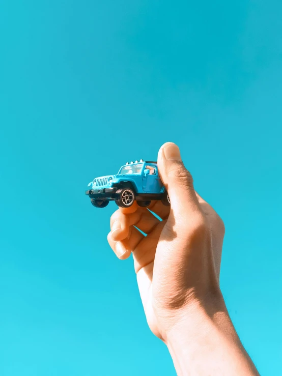 a person holding a toy car in their hand, by Sam Havadtoy, pexels contest winner, sky blue, made out of plastic, instagram picture, 15081959 21121991 01012000 4k