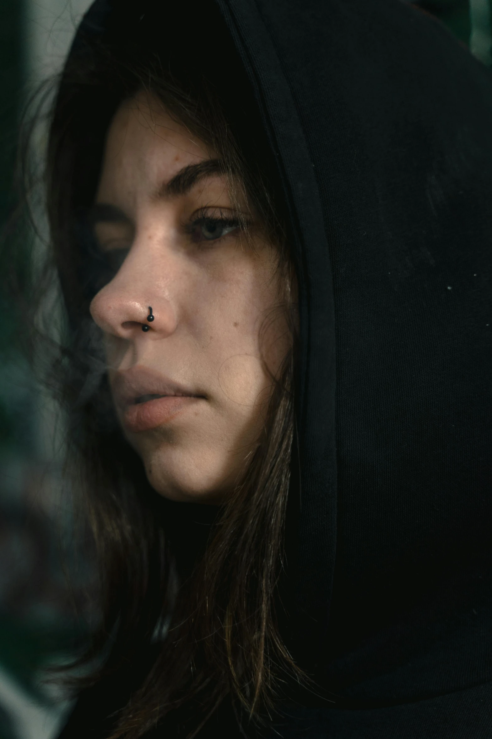 a close up of a person wearing a hoodie, a picture, inspired by Elsa Bleda, pexels contest winner, antipodeans, gothic girl smoking, a young female shaman, looking outside, thin nose