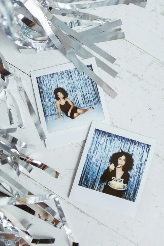 a couple of polaroids sitting on top of a table, inspired by Nan Goldin, holography, glittering silver ornaments, nathalie emmanuel, wearing disco suit, official product photo