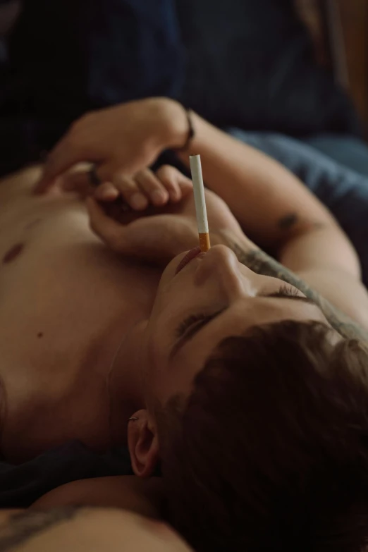 a man laying on a bed with a cigarette in his mouth, inspired by Nan Goldin, trending on pexels, hyperrealism, lesbians, hunter biden smoking crack, he is about 20 years old | short, mid-shot of a hunky