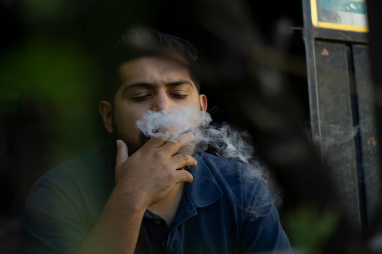 a man in a blue shirt smokes a cigarette, pexels contest winner, sayem reza, hunter biden smoking crack, thc, tear gas and smoke
