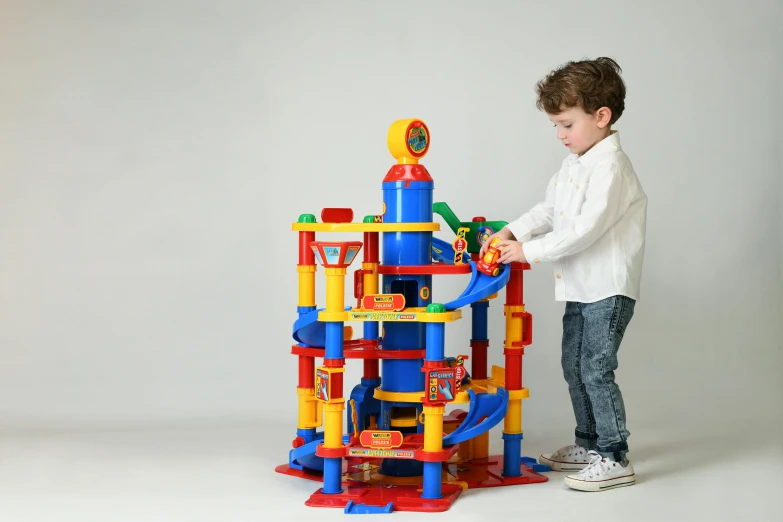 a little boy standing next to a toy tower, inspired by Rube Goldberg, instagram, bauhaus, multi colour, official product photo, oversized enginee, frontal shot