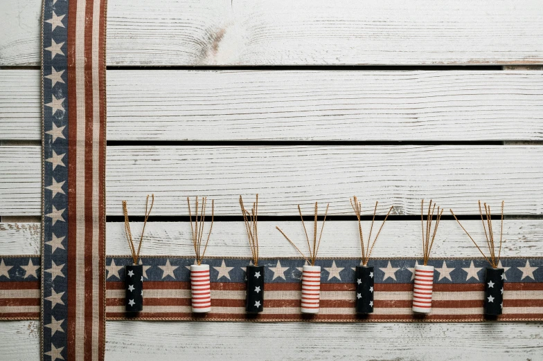 a row of toothpicks sitting on top of an american flag, an album cover, by Emma Andijewska, trending on pexels, folk art, :6 smoke grenades, background image, on wood, presents