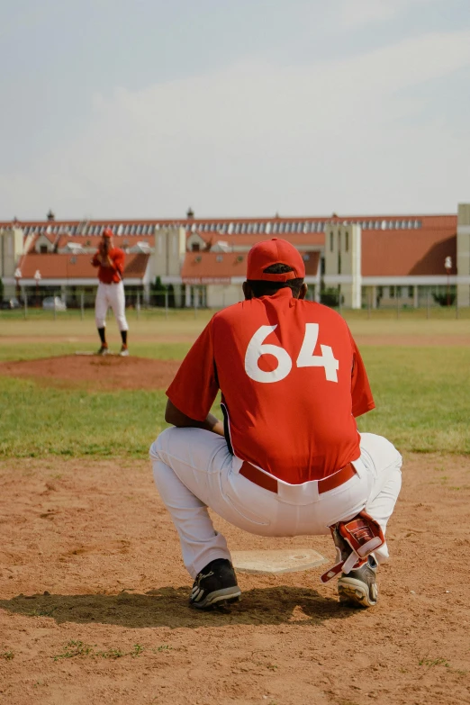 a baseball player holding a bat on top of a field, an album cover, by Greg Spalenka, pexels contest winner, red uniform, man sitting facing away, panoramic, malika favre