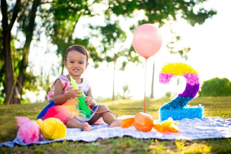 a baby sitting on top of a blanket next to a bunch of balloons, pexels contest winner, having a picnic, 2 2 years old, ( colorful ), riyahd cassiem