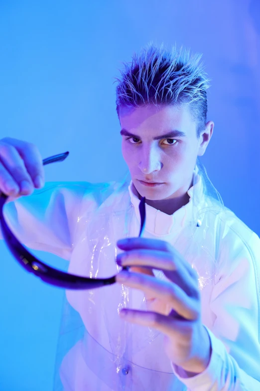 a man in a white shirt holding a pair of scissors, inspired by Adrian Zingg, wearing futuristic clothing, lab coat, performing, blue steel