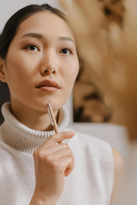 a woman brushing her teeth in front of a mirror, inspired by Ruth Jên, trending on pexels, hyperrealism, holding pencil, ethnicity : japanese, pondering, with a pointed chin