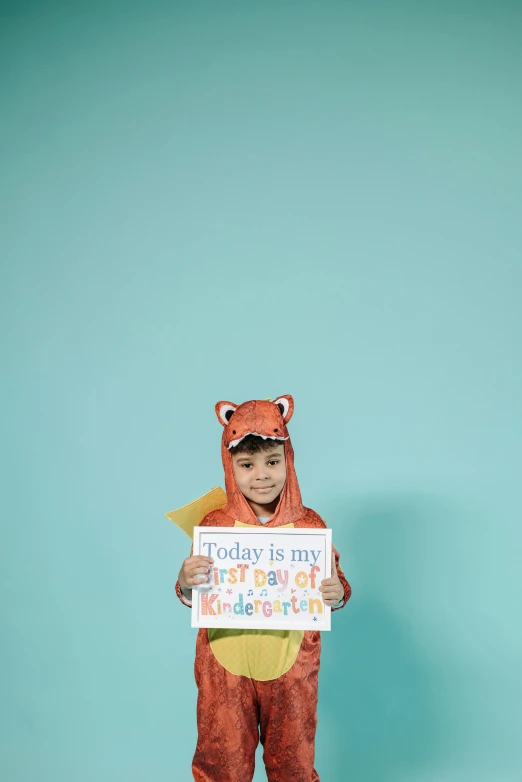 a little boy in a bear costume holding a sign, shutterstock contest winner, orange and teal color, ‘raya and the last dragon’ etc, studio portrait photo, student