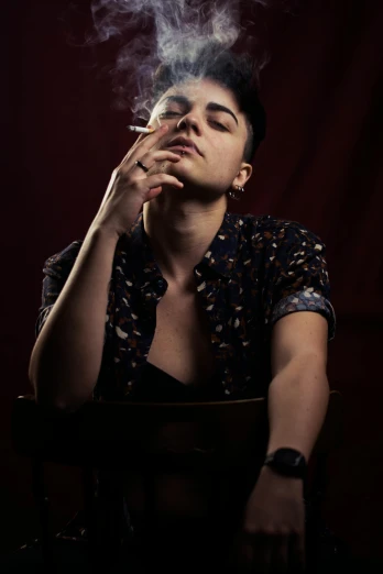 a man sitting in a chair smoking a cigarette, an album cover, inspired by Elsa Bleda, pexels contest winner, non binary model, confident pose, (night), ramil sunga