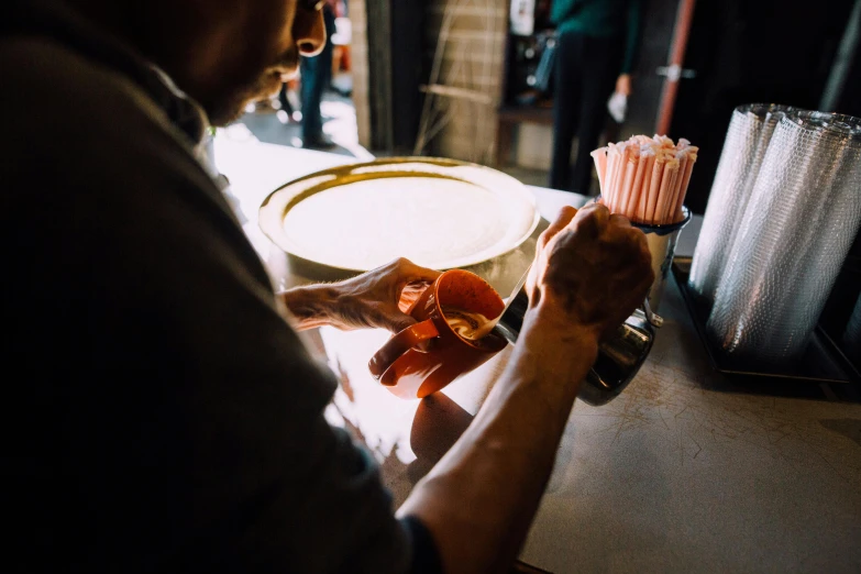 a man that is standing in front of a counter, by Matt Cavotta, trending on unsplash, maple syrup & hot fudge, copper cup, working in the forge, popcorn machine