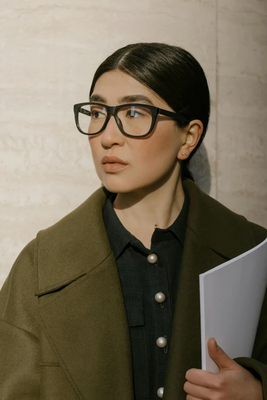 a woman in glasses holding a piece of paper, inspired by Ruth Jên, gemma chan, androgyny, wearing a brown, detail shot