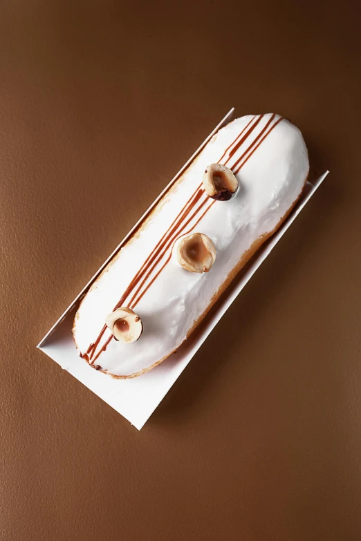 a donut sitting on top of a brown table, shaped like a yacht, long chin, white with gold accents, edouard caplain