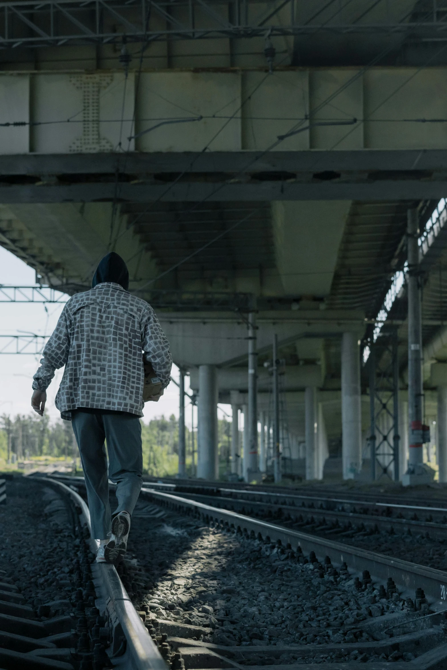 a man walking on train tracks under a bridge, action thriller, concerned, 8 k movie still, filmstill