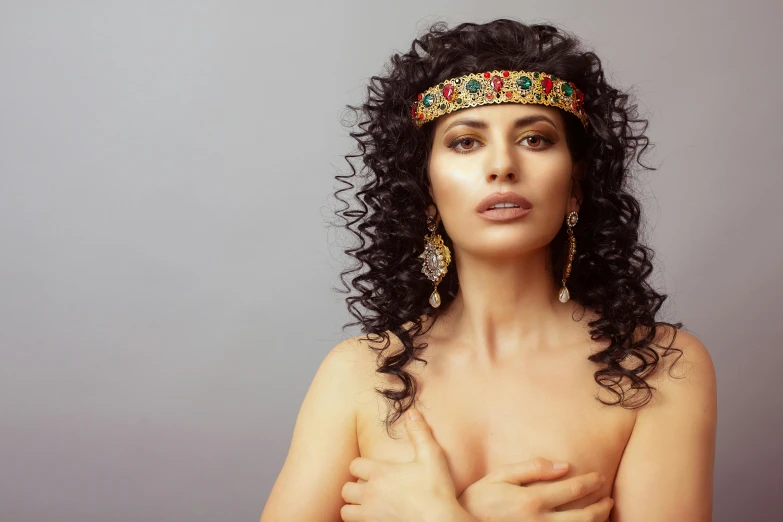 a woman with curly hair wearing a headband, inspired by Hedi Xandt, trending on pexels, renaissance, arabian wrestling woman, jeweled costume, assyrian, brunette woman