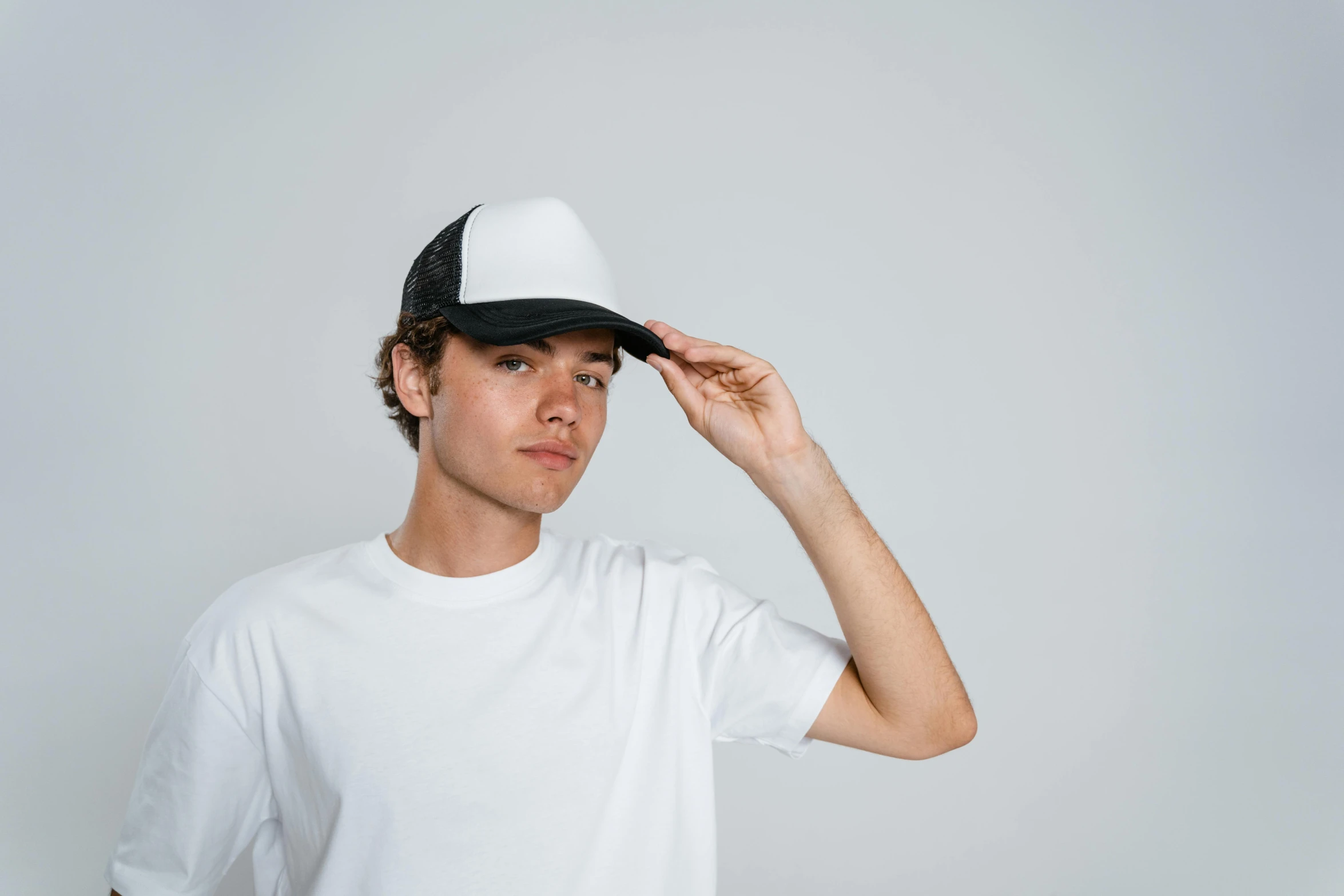 a young man wearing a white t - shirt and a black hat, pexels contest winner, renaissance, trucker hat, gradient white to silver, front, without text