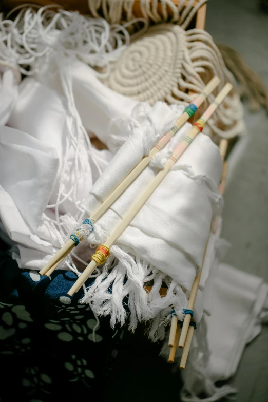 a basket that has some chopsticks in it, inspired by Cerith Wyn Evans, unsplash, process art, white sarong, detail shot, glass and gold pipes, tie-dye