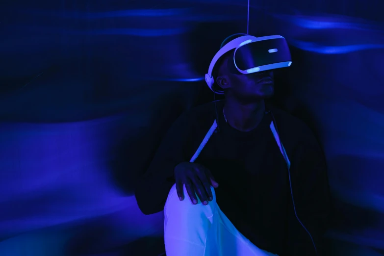 a man wearing a virtual reality headset in a dark room, pexels, afrofuturism, brightly lit blue room, indigo, sleepy, raytracing on