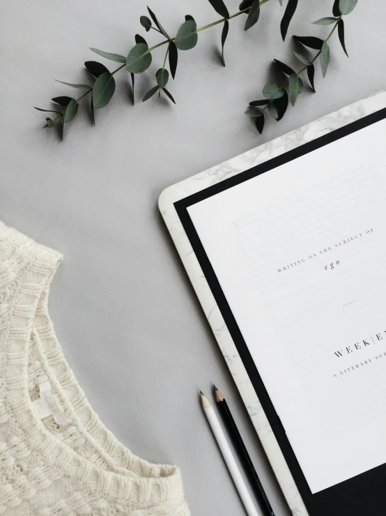 a tablet computer sitting on top of a table next to a cup of coffee, an album cover, by Arabella Rankin, trending on unsplash, ivory and black marble, calligraphy border, photoshoot for skincare brand, service ticket close up