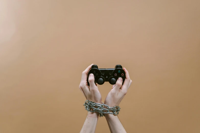 a person holding a video game controller in their hands, an album cover, inspired by Elsa Bleda, trending on pexels, barbed wire, minimalist photo, metal gauntlet, playstation 3