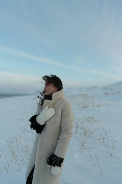 a woman standing on top of a snow covered field, an album cover, inspired by Konstantin Vasilyev, low quality photo, ☁🌪🌙👩🏾, near lake baikal, sangsoo jeong