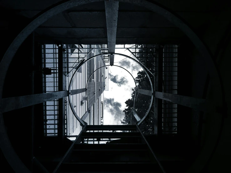 a black and white photo of a window in a building, pexels contest winner, brutalism, round clouds, look down a cellar staircase, view from below, spaceship window