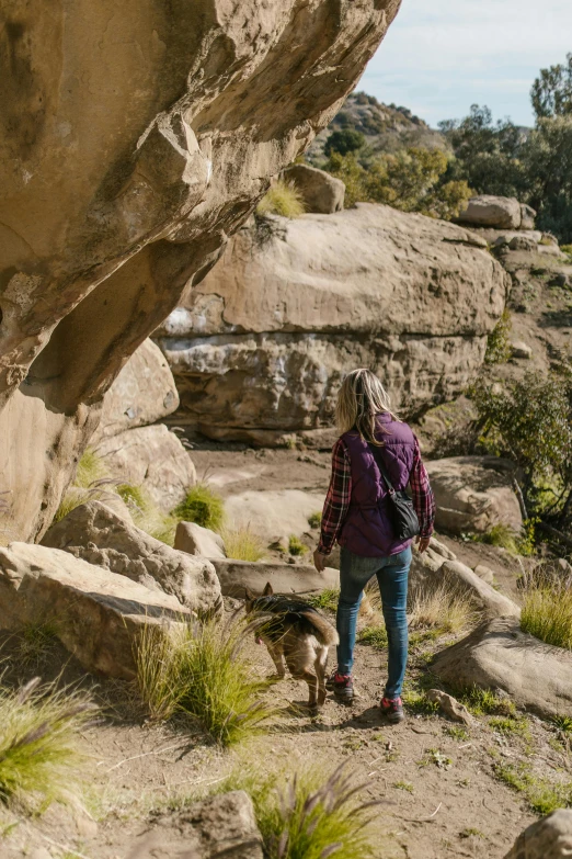 a woman walking a dog on a rocky trail, aqueduct and arches, aussie, boulders, cave exploration