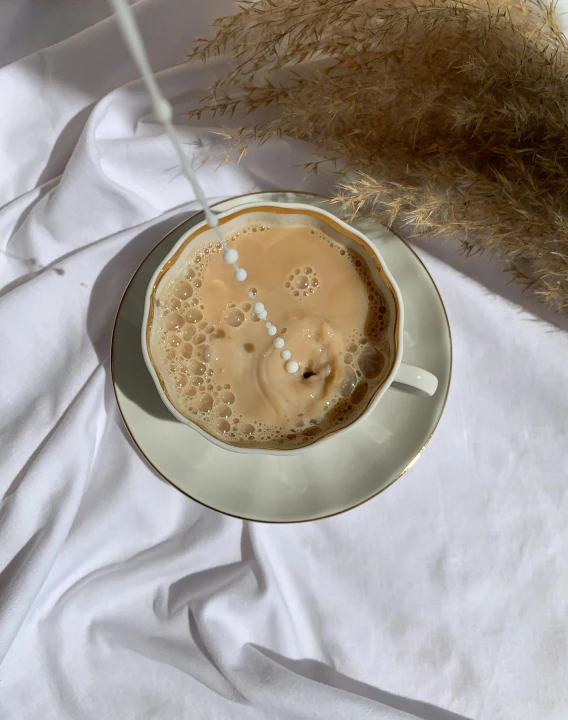 a cup of coffee sitting on top of a white table, by Emma Andijewska, flowing milk, low quality photo, threads, thumbnail