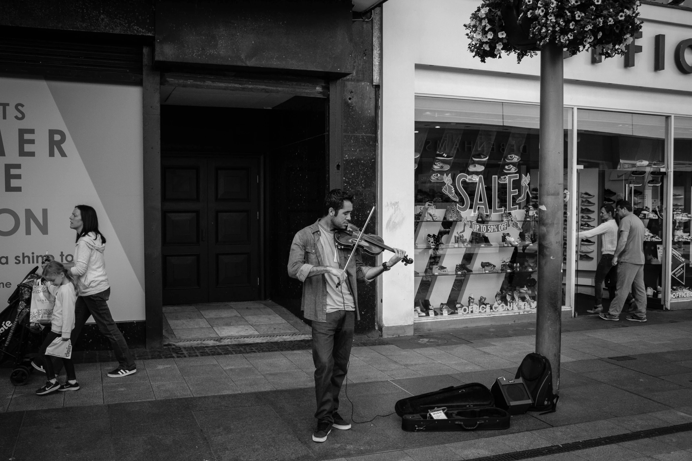 a man playing a violin on a city street, a black and white photo, azores, in scotland, lowres, tourist photo