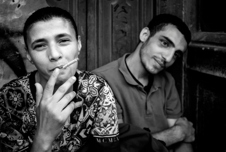 a black and white photo of two men smoking, a portrait, by Youssef Howayek, flickr, two young men, male and female, around 1 9 years old, taken in the late 2000s